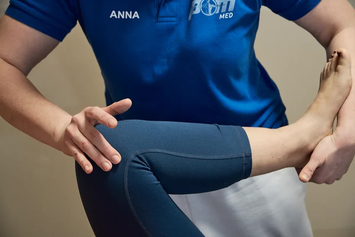 Physiotherapeutin der POM MED mobilisiert das Bein einer Patientin auf der Behandlungsliege