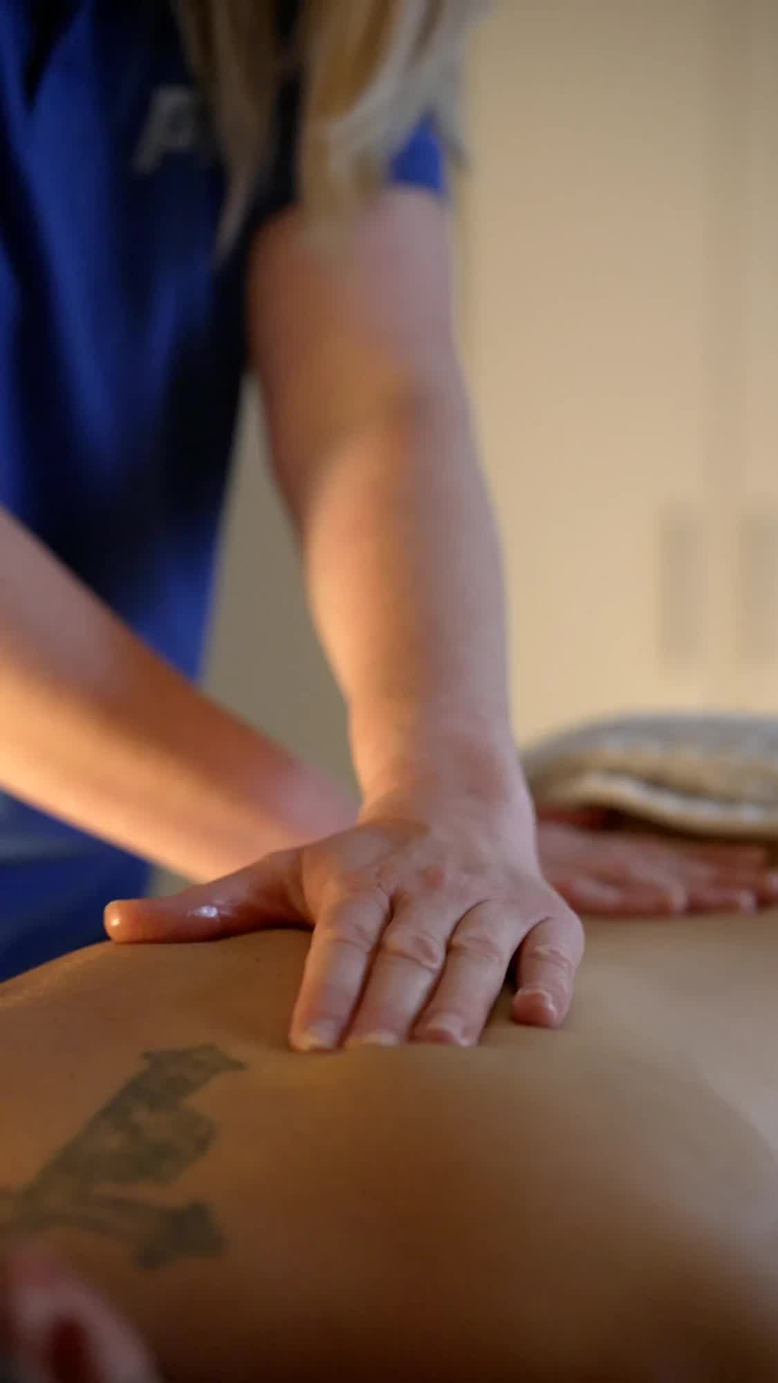 Therapeutin der POM MED massiert mit der Hand den Rücken eines Patienten