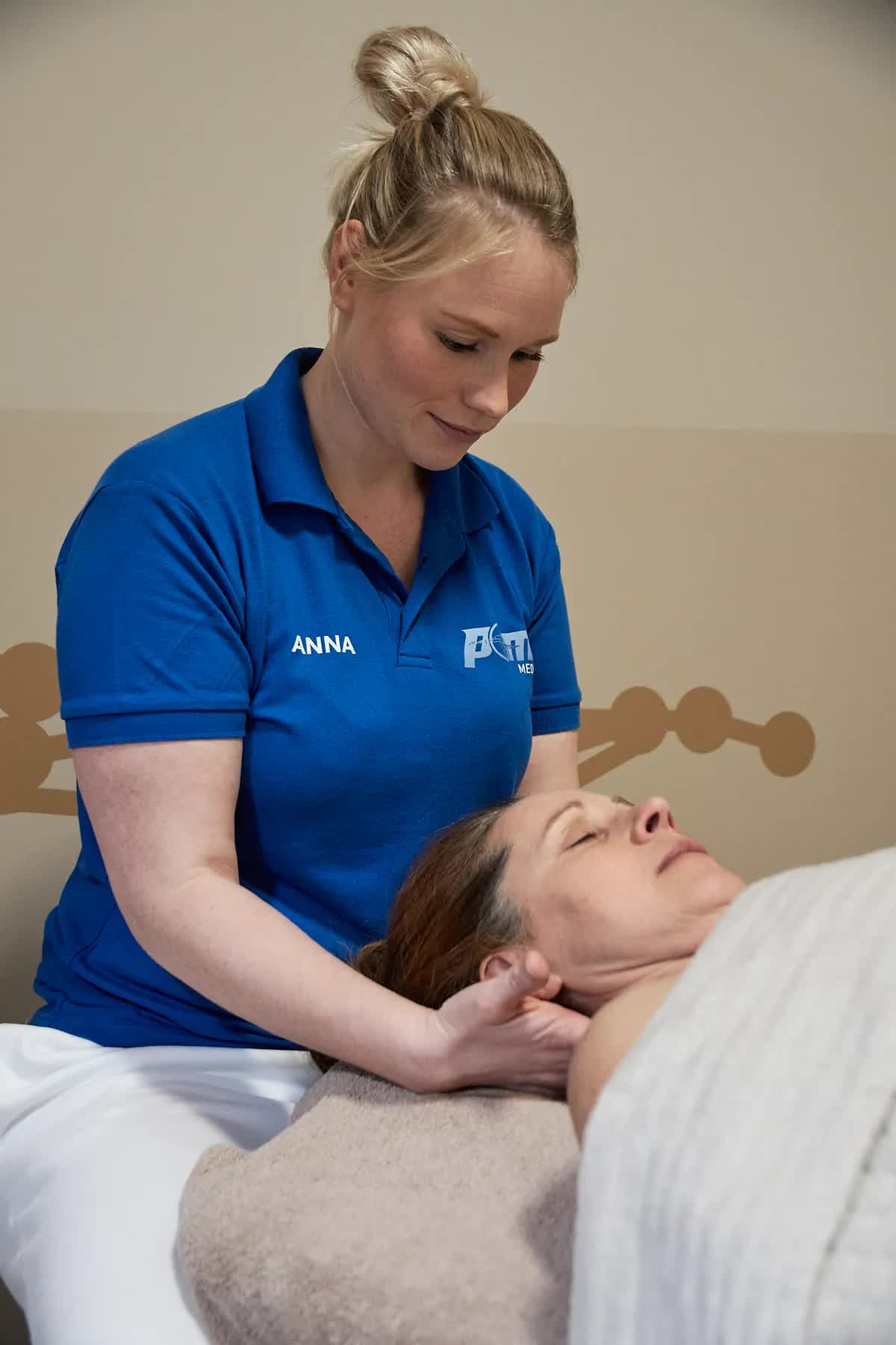 Physiotherapeutin der POM MED behandelt sanft den Nacken einer Patientin