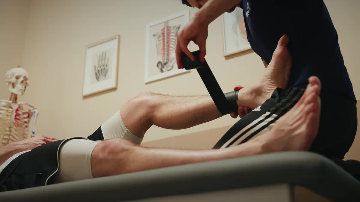 Physiotherapeut der POM MED behandelt das Bein eines Patienten auf der Liege
