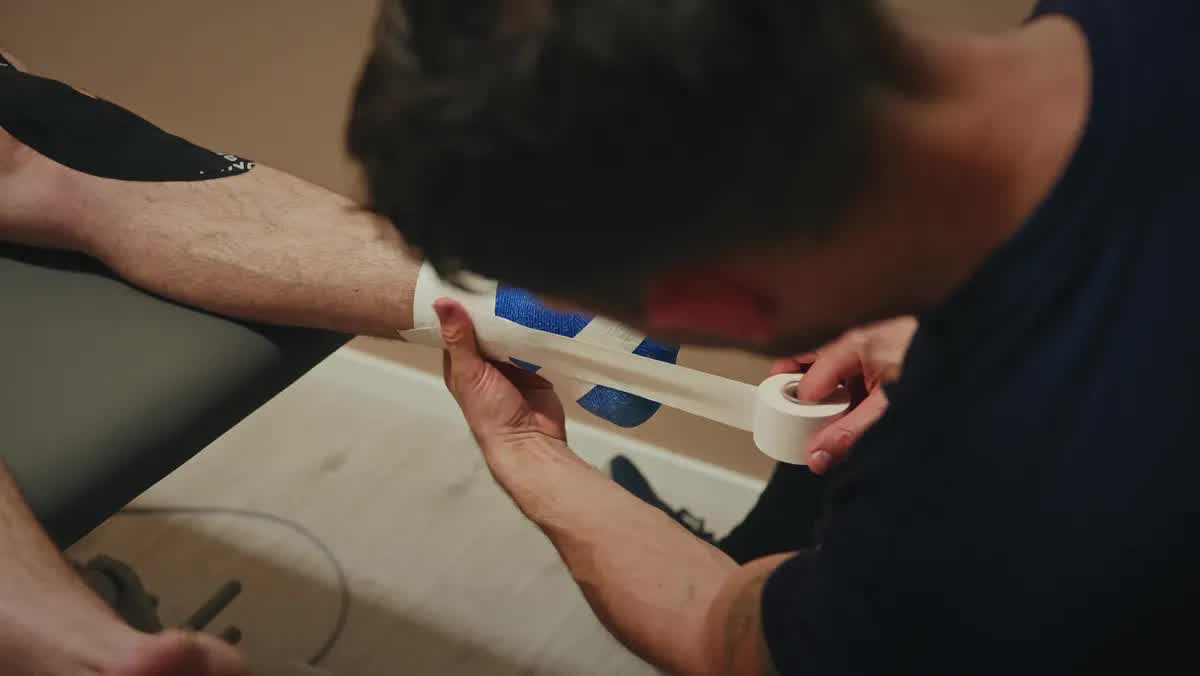 Physiotherapeut der POM MED legt ein Tape am Fuß eines Patienten an