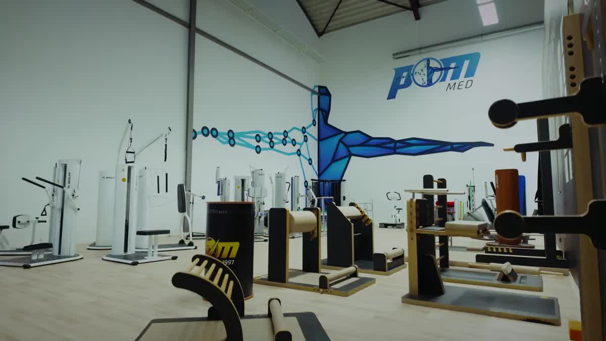 Große Trainingsfläche mit medizinischen Geräten und dem POM-MED-Logo an der Wand